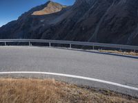 an empty mountain road next to a highway with several vehicles driving along it and in the background is mountains