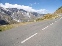 two long, straight road winds through mountains and a valley below it with snow capped peaks