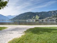 a scenic view of the mountains and a lake surrounded by trees with a fence in front