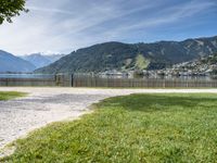 a scenic view of the mountains and a lake surrounded by trees with a fence in front