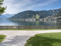 a scenic view of the mountains and a lake surrounded by trees with a fence in front