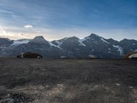 two people in tents are sitting at the bottom of a mountain on top of snow covered mountains