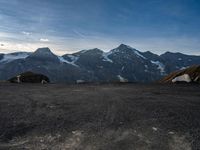 two people in tents are sitting at the bottom of a mountain on top of snow covered mountains