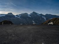 two people in tents are sitting at the bottom of a mountain on top of snow covered mountains