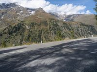 a man riding a motorcycle down a mountain road with mountains behind him behind him are trees