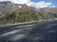 a man riding a motorcycle down a mountain road with mountains behind him behind him are trees