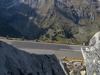 a person on a motorcycle riding down a road with mountains in the background and a highway winding in the distance