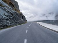 an asphalt road near some rocky and low mountains on a cloudy day to show the speed