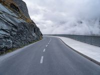 an asphalt road near some rocky and low mountains on a cloudy day to show the speed