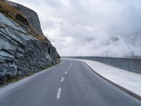 an asphalt road near some rocky and low mountains on a cloudy day to show the speed