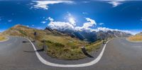 fish - eye lens of a road in the mountains next to two hills and some clouds