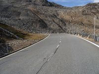 a motorcycle driving on the road between mountains and grass as a sign points to a right turn