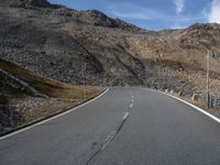 a motorcycle driving on the road between mountains and grass as a sign points to a right turn