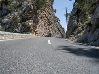 the highway has an old structure along it and tall steep cliffs behind it, making the curve a narrow