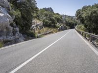 an empty highway in the mountains with pine trees surrounding it and rocky walls around it