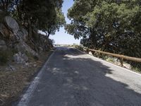 a bike on a mountain road beside trees and bushess in the hills around a bridge