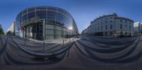 a street is surrounded by buildings that include a glass facade and large umbrellas on top