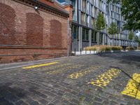 a long empty brick street with tall buildings in the background on a sunny day with some people walking around