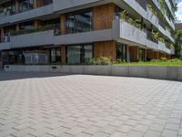 an open paved area with concrete walling, grass and a patio on one side