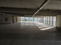 an empty parking space with large windows, concrete walls and long rows of flooring