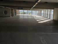 an empty parking space with large windows, concrete walls and long rows of flooring