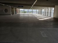 an empty parking space with large windows, concrete walls and long rows of flooring