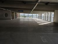 an empty parking space with large windows, concrete walls and long rows of flooring