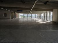 an empty parking space with large windows, concrete walls and long rows of flooring