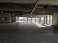 an empty parking space with large windows, concrete walls and long rows of flooring