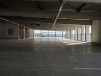 an empty parking space with large windows, concrete walls and long rows of flooring