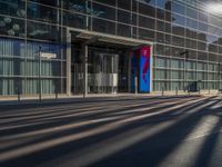 the sunlight reflects from several windows in a large building onto the street from outside the building