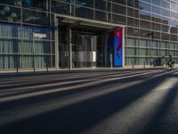 the sunlight reflects from several windows in a large building onto the street from outside the building