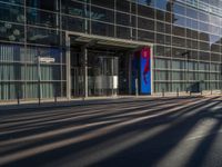 the sunlight reflects from several windows in a large building onto the street from outside the building