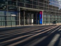 the sunlight reflects from several windows in a large building onto the street from outside the building