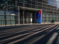 the sunlight reflects from several windows in a large building onto the street from outside the building