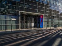 the sunlight reflects from several windows in a large building onto the street from outside the building