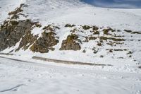 person skiing down the side of the mountain on a slope of snow with rocks in the distance