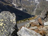 there are two vehicles parked near the side of the road and some rocks on the mountain