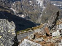 there are two vehicles parked near the side of the road and some rocks on the mountain