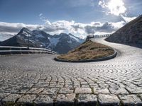 an empty pathway that is winding through the mountain valley of mountains and grassy slopes with cobbles on the floor