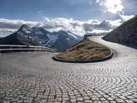 an empty pathway that is winding through the mountain valley of mountains and grassy slopes with cobbles on the floor