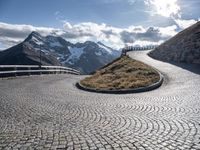 an empty pathway that is winding through the mountain valley of mountains and grassy slopes with cobbles on the floor