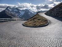 an empty pathway that is winding through the mountain valley of mountains and grassy slopes with cobbles on the floor