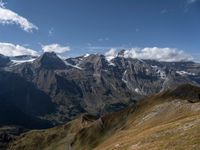 a lone person stands in the mountains, staring out at snow on top of the peaks