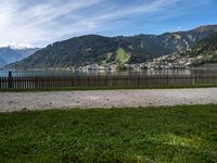 a man with a bike leaning against a fence in front of the water, in front of mountains