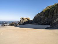 a sandy beach near the ocean and cliffs with water nearby on a clear day with no one in sight