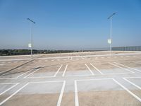 a empty parking lot with several lights in front of it and a hill on the side