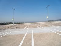 a empty parking lot with several lights in front of it and a hill on the side