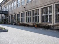 a street in an old part of europe with benches and tables by the windows with plants growing out