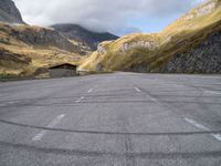 an empty parking lot with no one standing on it, near a mountain range in the mountains